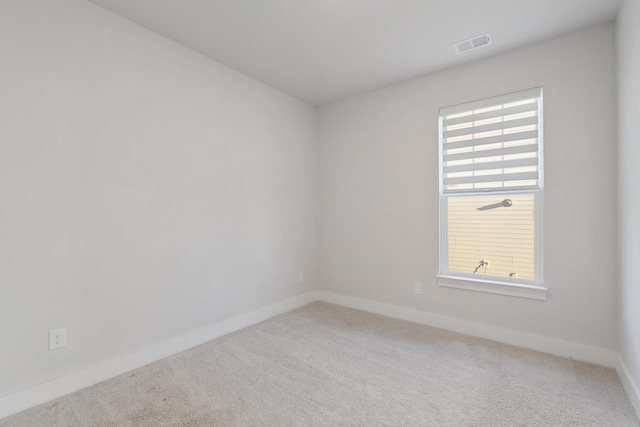 spare room featuring carpet, visible vents, and baseboards