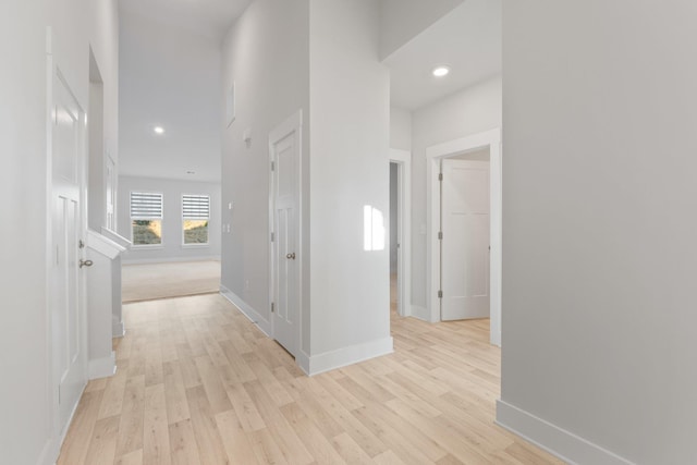 corridor with light wood-style floors, baseboards, and recessed lighting