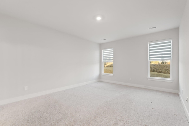 unfurnished room with light colored carpet, visible vents, and baseboards