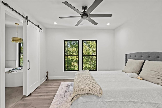 bedroom featuring ceiling fan, hardwood / wood-style flooring, and a barn door