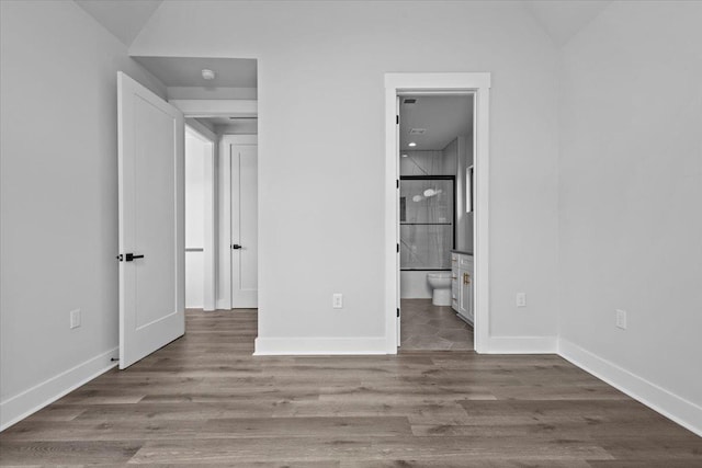 unfurnished bedroom with ensuite bathroom, lofted ceiling, and dark hardwood / wood-style flooring