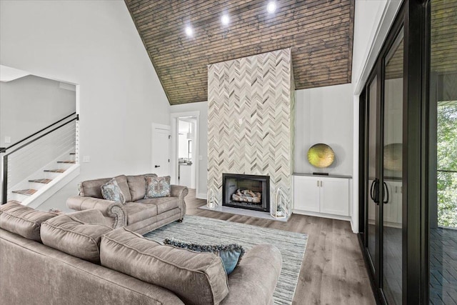 living room featuring high vaulted ceiling, a healthy amount of sunlight, a tiled fireplace, and hardwood / wood-style floors