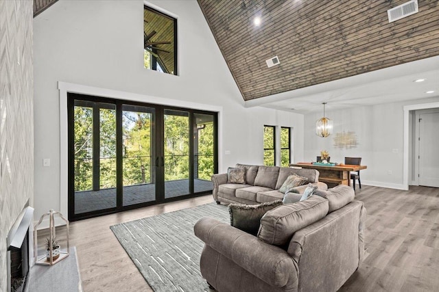 living room with a high ceiling, a wealth of natural light, a chandelier, and light wood-type flooring