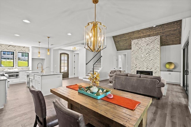 dining room with plenty of natural light, a tile fireplace, a notable chandelier, and hardwood / wood-style flooring