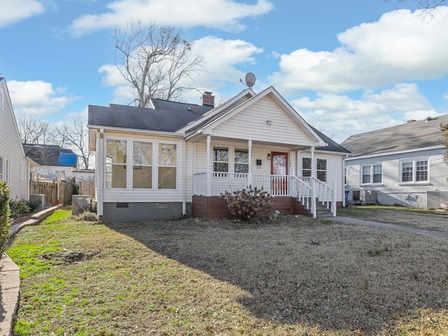 bungalow-style house featuring a front lawn, a porch, and central air condition unit