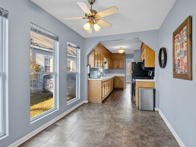 kitchen featuring ceiling fan, sink, backsplash, and stove