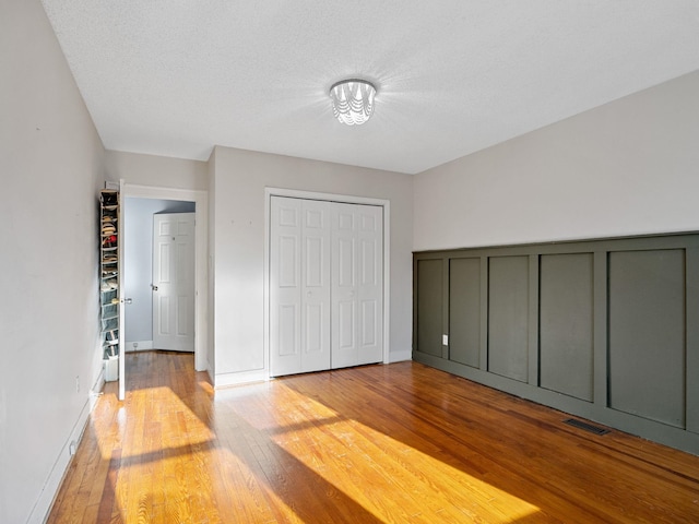 unfurnished bedroom featuring light hardwood / wood-style floors, a textured ceiling, and a closet