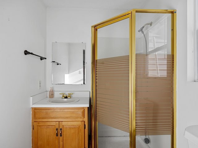 bathroom featuring a shower with shower door, toilet, and vanity