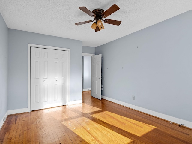 unfurnished bedroom with ceiling fan, a closet, a textured ceiling, and hardwood / wood-style floors