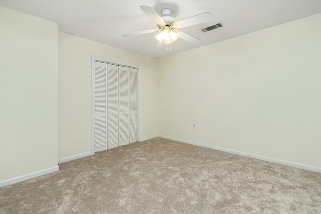 unfurnished bedroom with ceiling fan, light colored carpet, and a closet