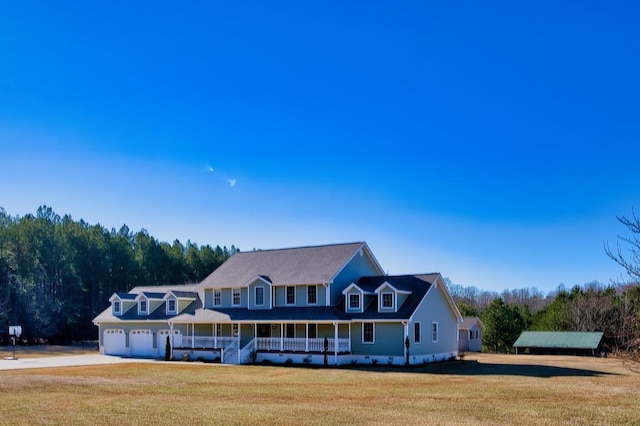 view of front of house featuring covered porch, a front yard, and a garage