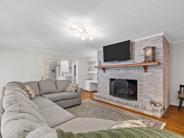 living room featuring a brick fireplace, crown molding, a textured ceiling, and hardwood / wood-style flooring