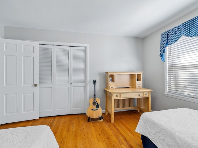 bedroom with a closet, multiple windows, and light hardwood / wood-style flooring