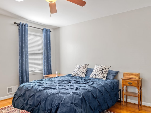 bedroom with ceiling fan, multiple windows, and hardwood / wood-style flooring