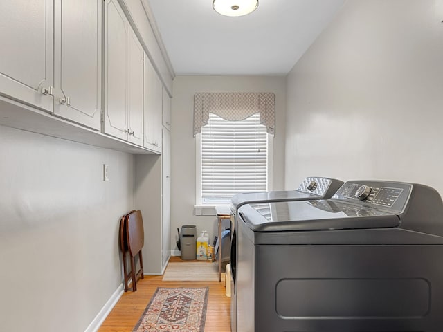 laundry room featuring light wood-type flooring, cabinets, and washing machine and clothes dryer