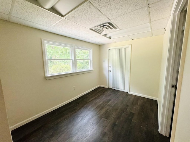 unfurnished bedroom featuring dark hardwood / wood-style floors and a drop ceiling