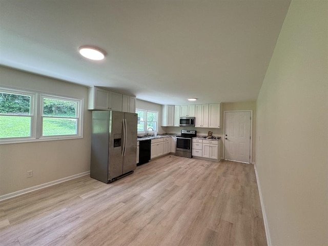 kitchen with sink, white cabinetry, appliances with stainless steel finishes, and light hardwood / wood-style flooring