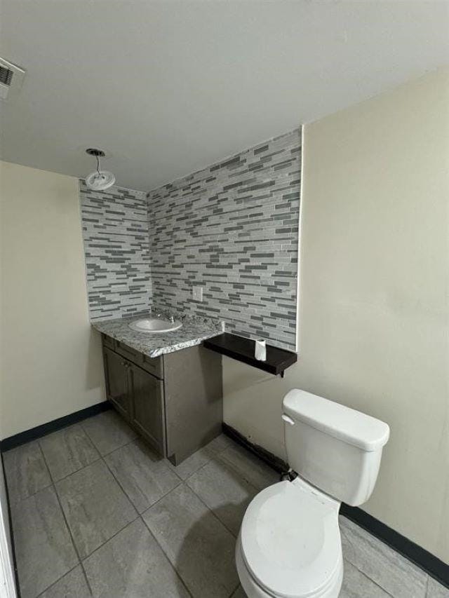 bathroom featuring decorative backsplash, tile patterned floors, toilet, and vanity