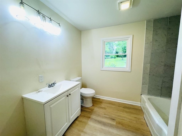 bathroom with toilet, vanity, a bathtub, and hardwood / wood-style flooring