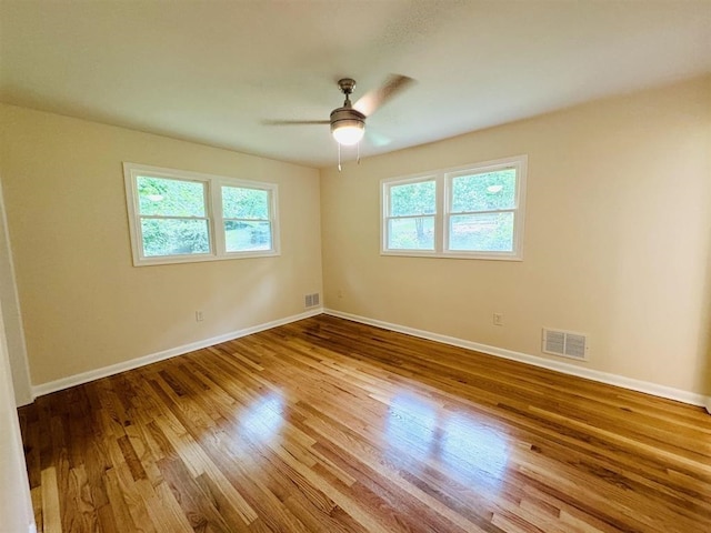 spare room featuring ceiling fan, a wealth of natural light, and light hardwood / wood-style flooring