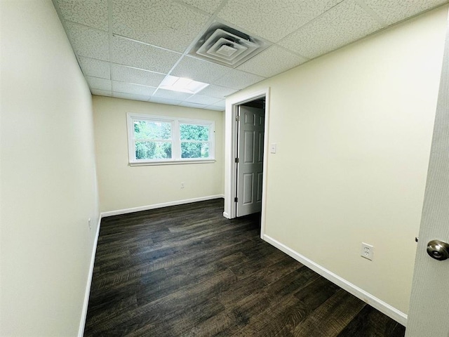 spare room featuring a paneled ceiling and dark hardwood / wood-style flooring