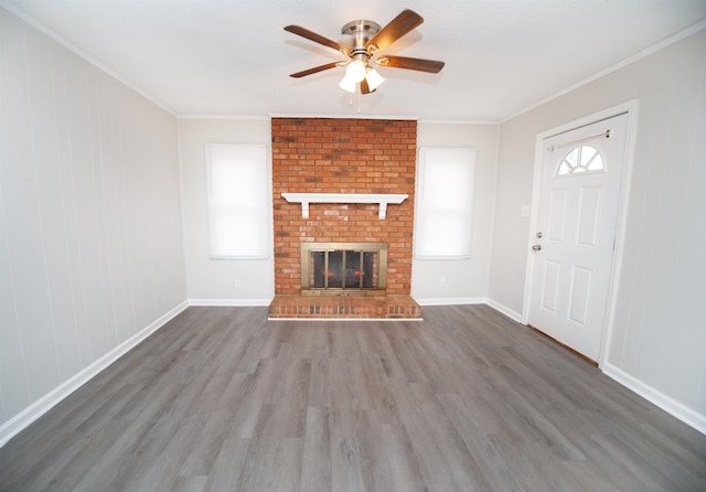 unfurnished living room featuring a brick fireplace, dark hardwood / wood-style floors, ornamental molding, and ceiling fan