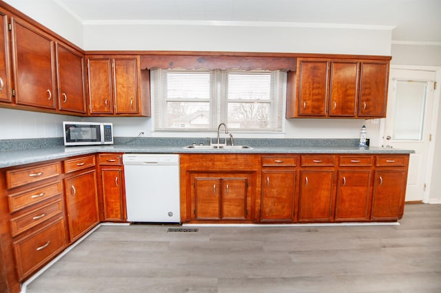 kitchen featuring white dishwasher, sink, crown molding, and light wood-type flooring