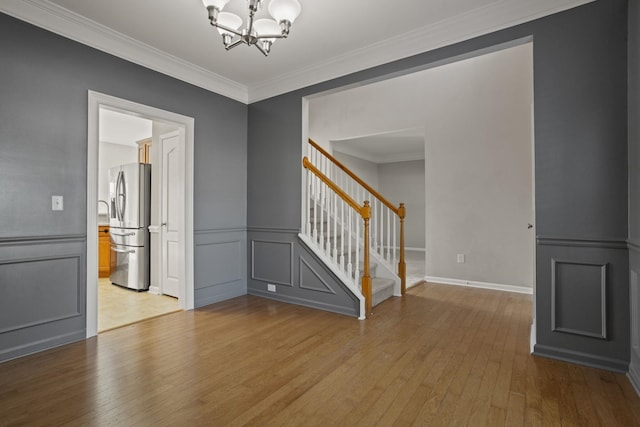 unfurnished room featuring ornamental molding, a chandelier, and light hardwood / wood-style flooring