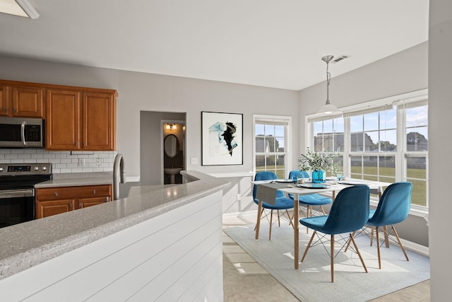 kitchen featuring decorative light fixtures, plenty of natural light, appliances with stainless steel finishes, and tasteful backsplash