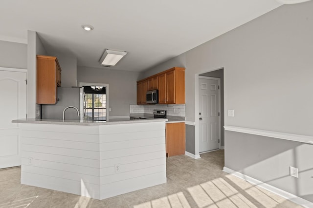 kitchen with kitchen peninsula, backsplash, sink, and stainless steel appliances