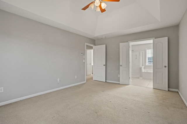 unfurnished bedroom featuring light carpet, ceiling fan, connected bathroom, and a tray ceiling