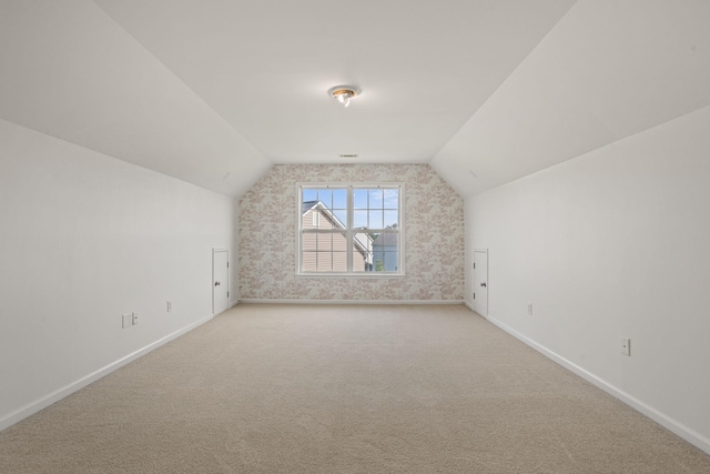 bonus room with light colored carpet and lofted ceiling