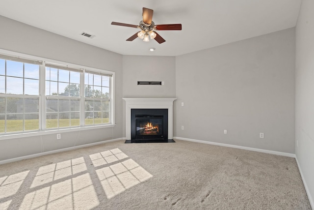 unfurnished living room featuring light carpet, ceiling fan, and a wealth of natural light