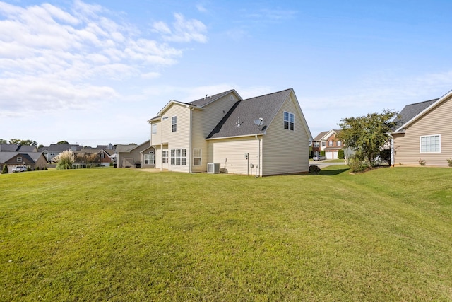 rear view of property featuring central AC unit and a lawn