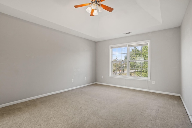 carpeted spare room featuring ceiling fan and a raised ceiling