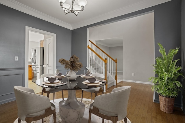 dining space featuring dark wood-type flooring, crown molding, and an inviting chandelier