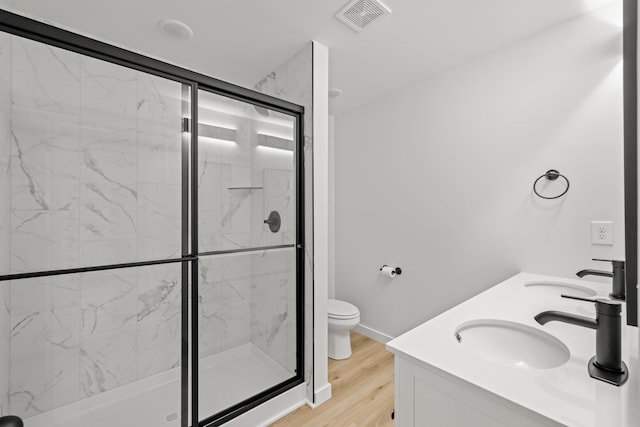 bathroom featuring hardwood / wood-style floors, toilet, a shower with door, and vanity