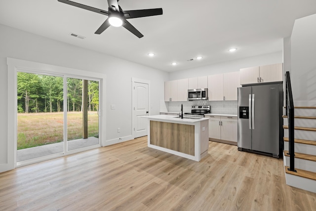 kitchen featuring light wood-type flooring, ceiling fan, appliances with stainless steel finishes, and a kitchen island with sink