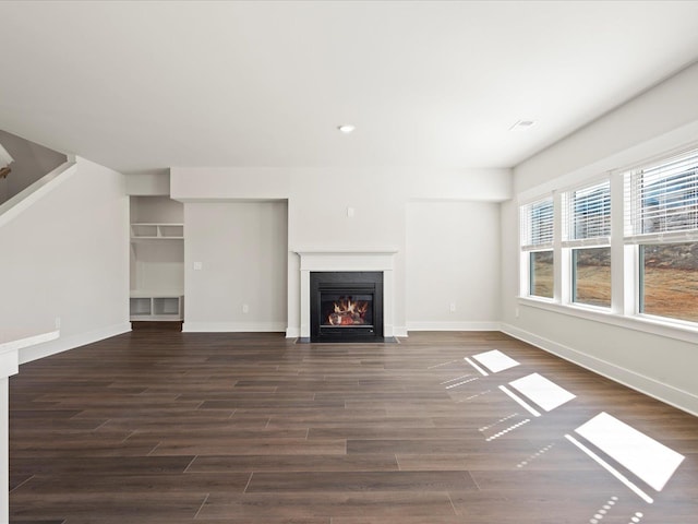 unfurnished living room featuring dark wood-style floors, a fireplace with flush hearth, baseboards, and recessed lighting