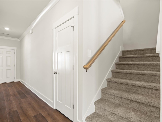 staircase with baseboards, visible vents, wood finished floors, and ornamental molding