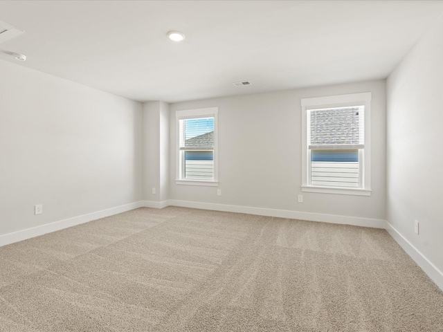 spare room with light carpet, visible vents, and baseboards