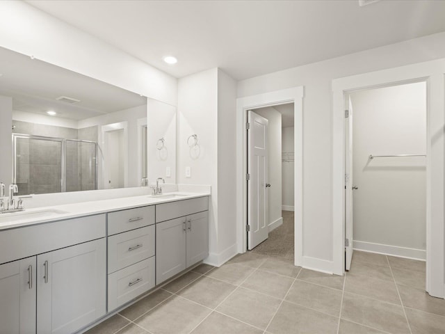 full bath featuring a stall shower, tile patterned flooring, a sink, and a walk in closet