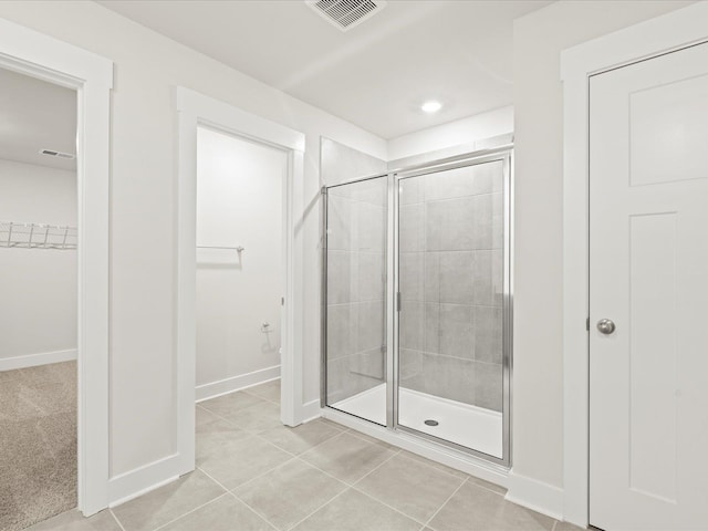 bathroom with visible vents, baseboards, tile patterned floors, a walk in closet, and a shower stall