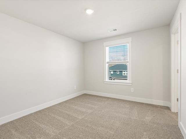 spare room with light colored carpet, visible vents, and baseboards