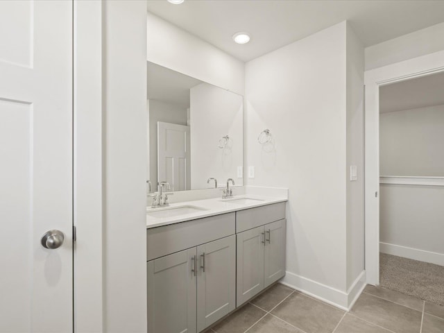 full bath featuring double vanity, tile patterned flooring, baseboards, and a sink