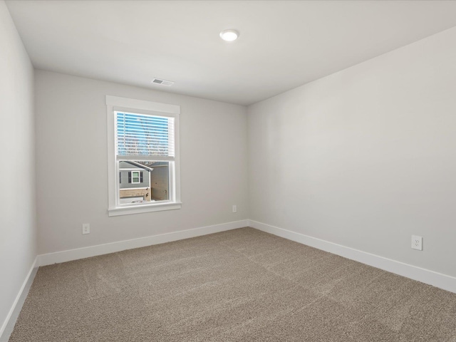 empty room featuring carpet floors, visible vents, and baseboards