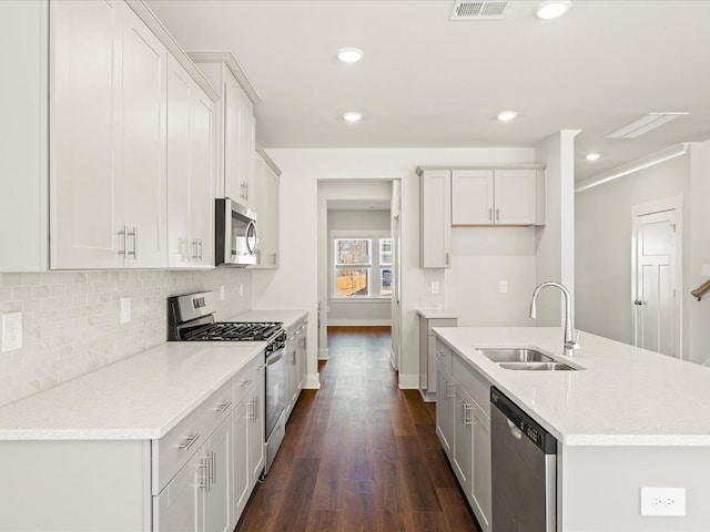 kitchen with visible vents, dark wood-type flooring, a sink, stainless steel appliances, and backsplash