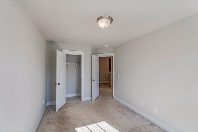 unfurnished bedroom featuring light carpet and a closet