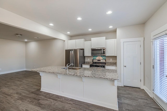 kitchen with a center island with sink, a kitchen bar, sink, white cabinetry, and appliances with stainless steel finishes