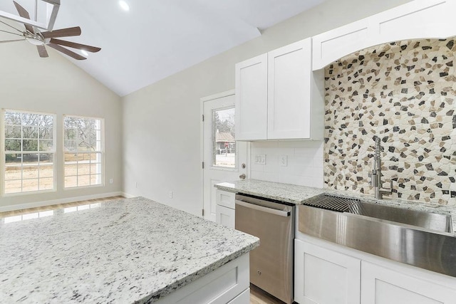 kitchen with decorative backsplash, dishwasher, light stone countertops, vaulted ceiling, and white cabinets